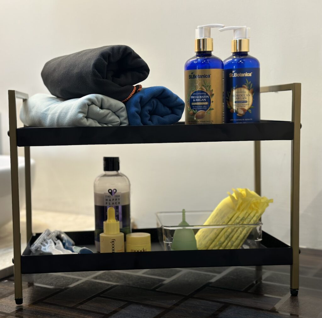 Towels, Shampoo, conditioner, razors, skincare, menstrual accessories on a bathroom stand