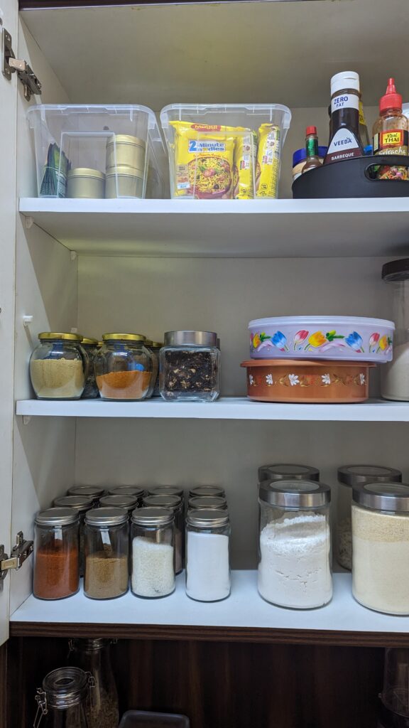 Glass jars with spices, plastic bins with stock food pantry