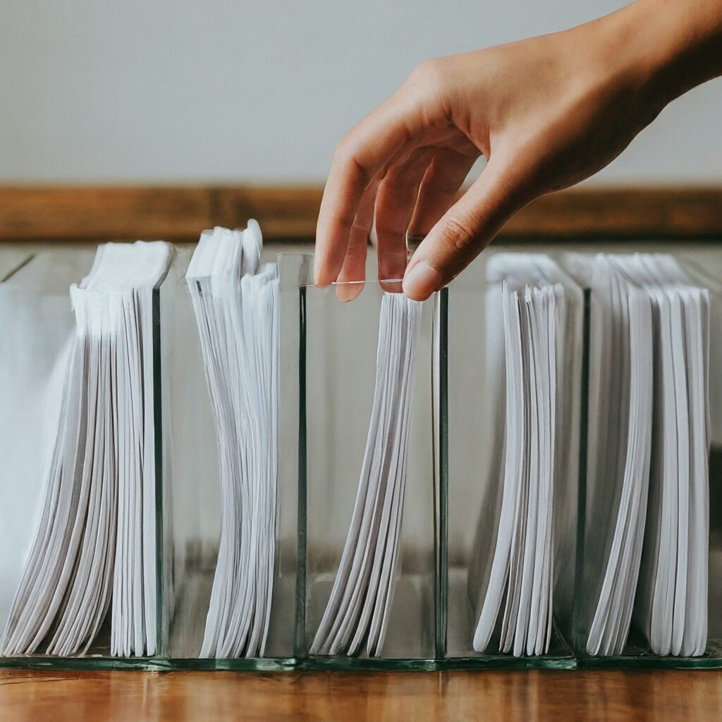 Multiple transparent tray kept one next to another into which papers are being sorted into by a hand
