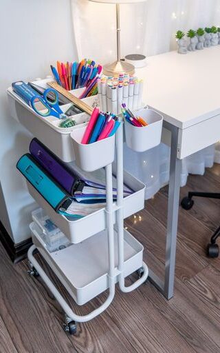 a rolling cart filled with stationery items next to a desk - clutterbug