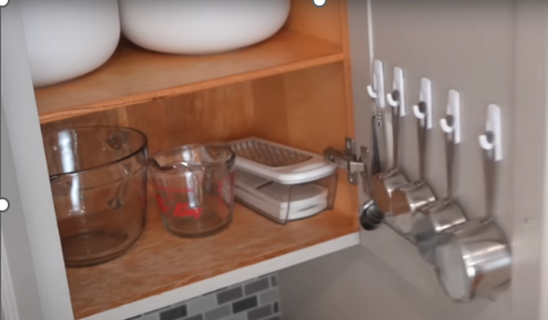 measuring cups hung on cabinet doors with adhesive strips