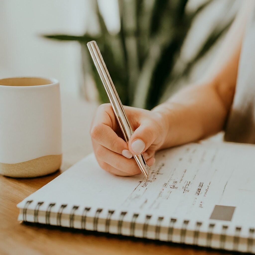 Person with a pen creating a to-do list with a coffee mug