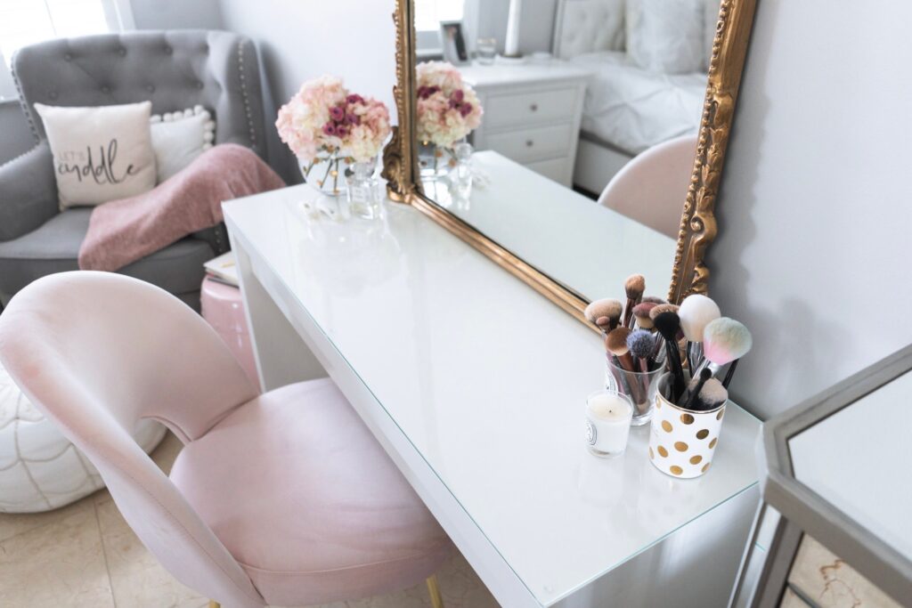 Clean top dressing table with flowers and make up brushes in front of a mirror