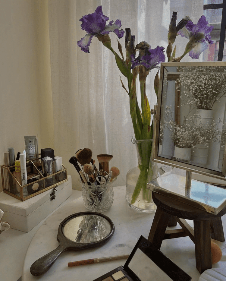 Messy dressing table with make up, mirror, flowers, make up brushes