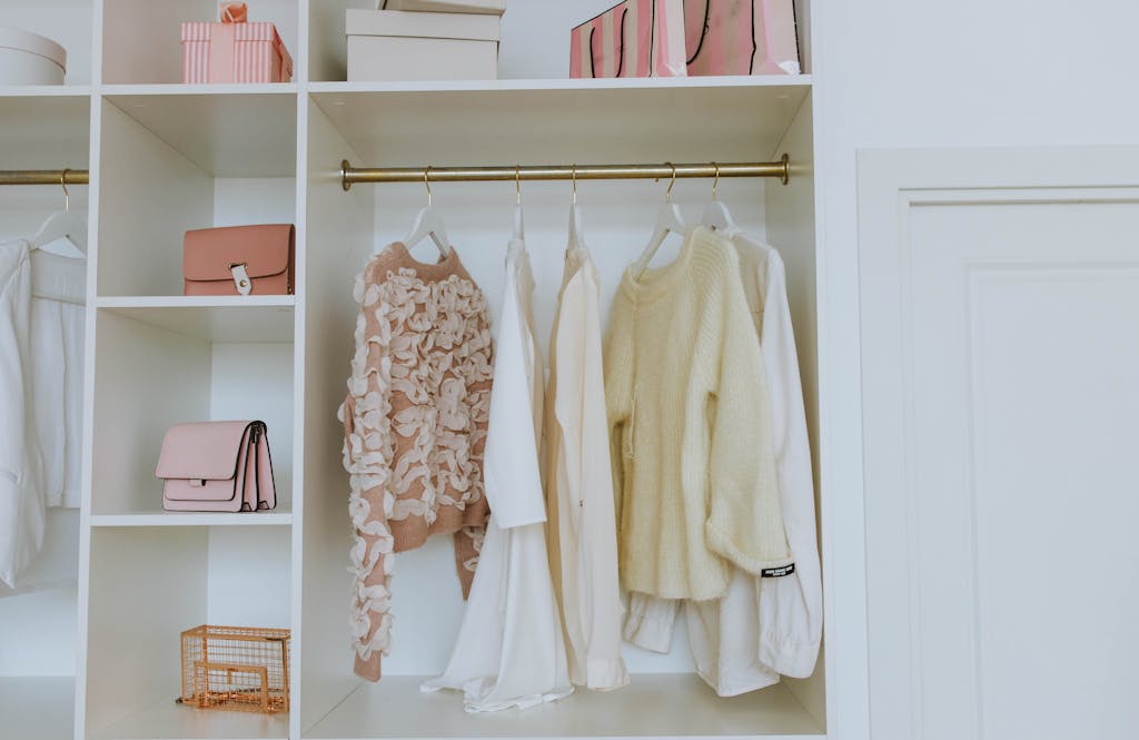 Organized White Wooden Closet with sweaters, shirts, purse